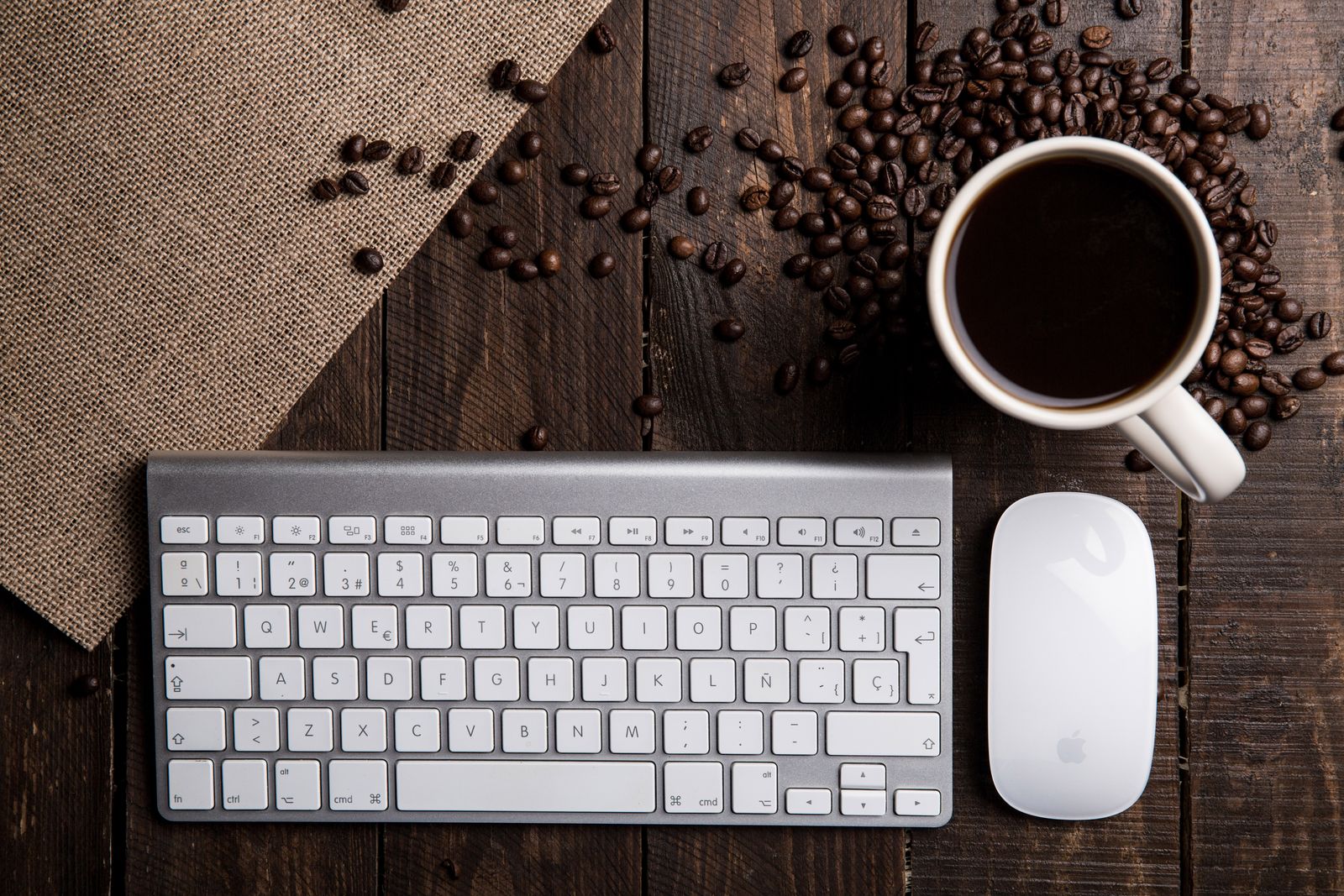 Real overhead photograph of a keyboard, mouse and coffee cup on a wooden desk